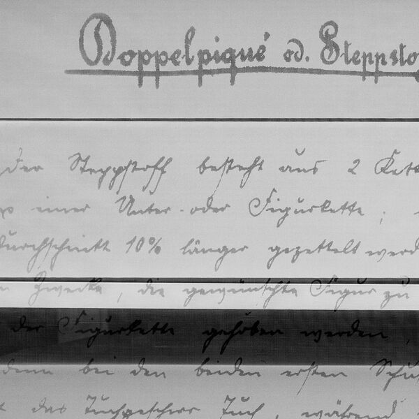 Nahansicht von historischen Archivboxen aus grauem Karton, die in altdeutscher Handschrift beschriftet ist.