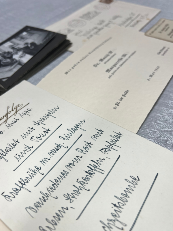Die Abbildung zeigt nebeneinander angeordnete historische Dokumente wie eine handschriftlich verfasste Hochzeitsspeisekarten und ein Fotoalbum mit Schwarzweifotografien der Familie.