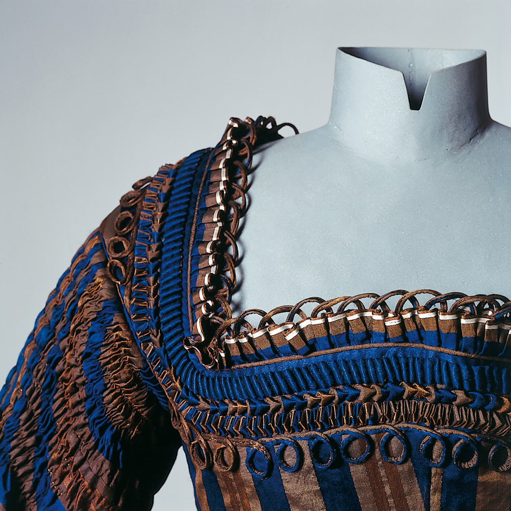 Eine Kleiderpuppe trägt eine aufwendig gearbeitete Schoßjacke (Schalk) aus Seide. Sie stammt aus Wackersberg und ist um 1860/70 datiert.