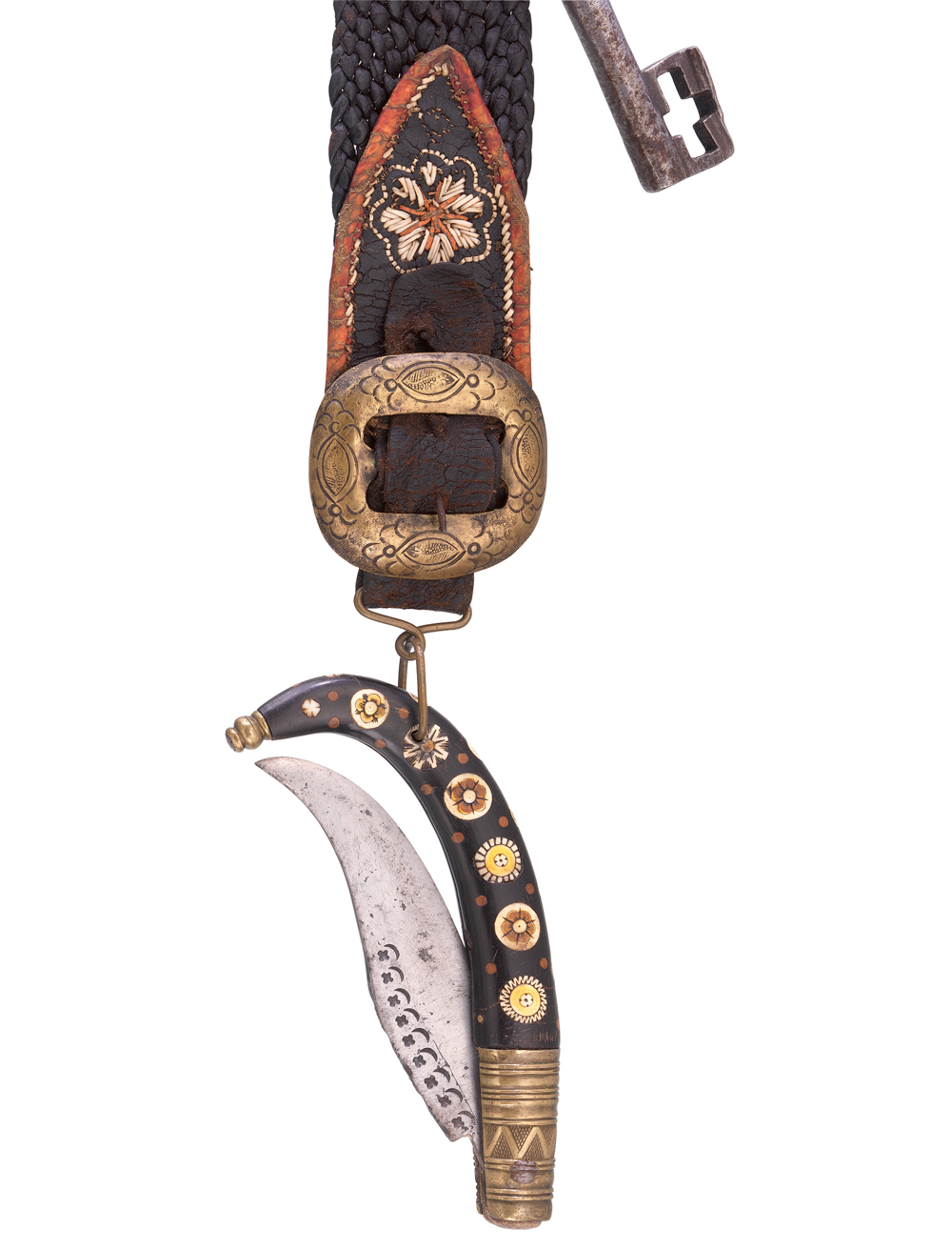 Dieser Gürtelriemen aus braunem Leder wurde Mitte des 19. Jahrhunderts in Tirol gefertigt. Seitlich an ihm ist ein rostiger Schlüssel befestigt, an der Messingschnalle pendelt ein mit Blumenintarsien verziertes Klappmesser.